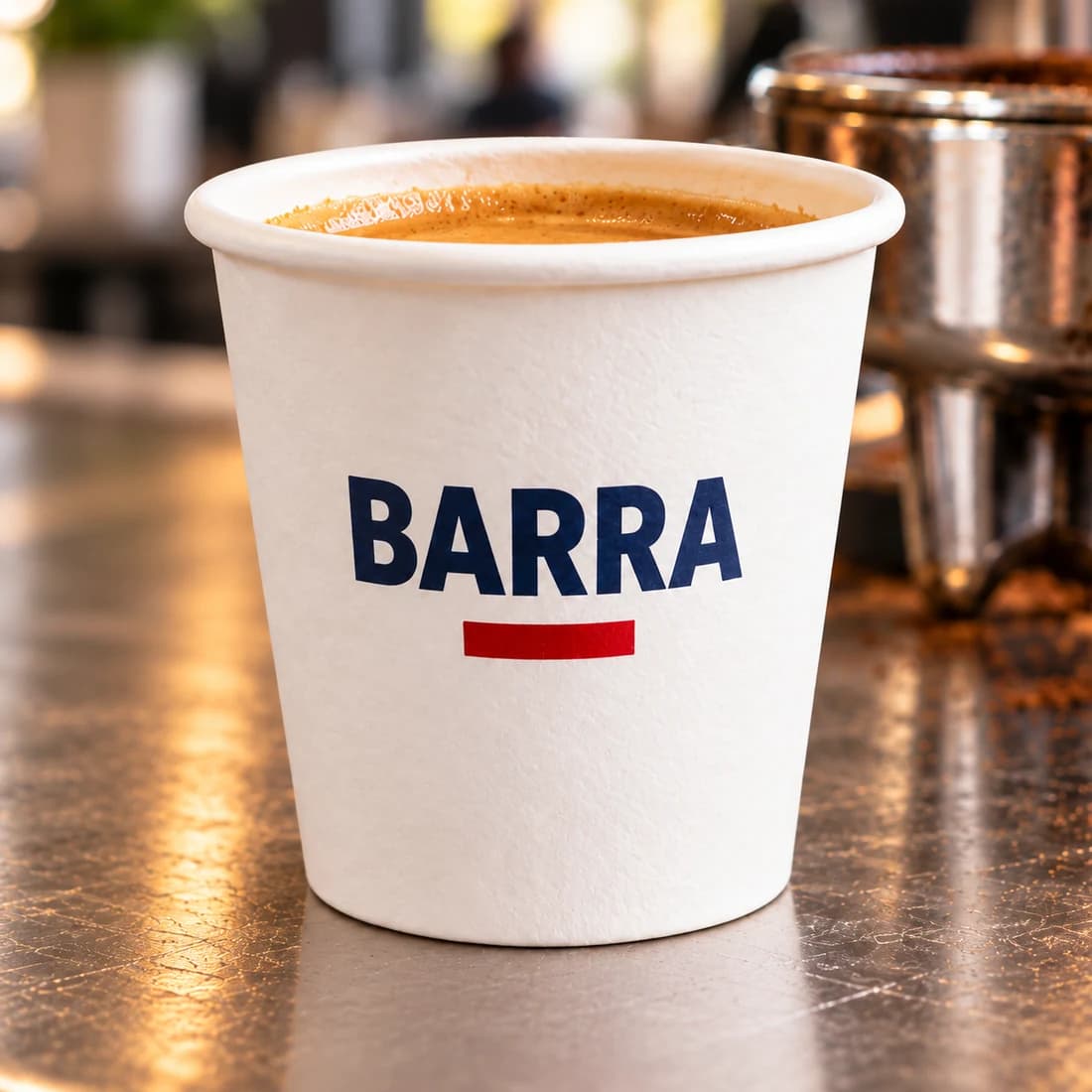 Primer plano de un vasito de papel de 2 oz con la marca BARRA sobre una barra de café