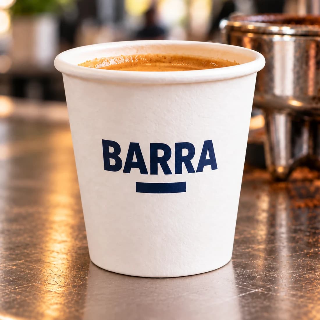 Close-up of a BARRA-branded 2 oz paper espresso cup on a café counter
