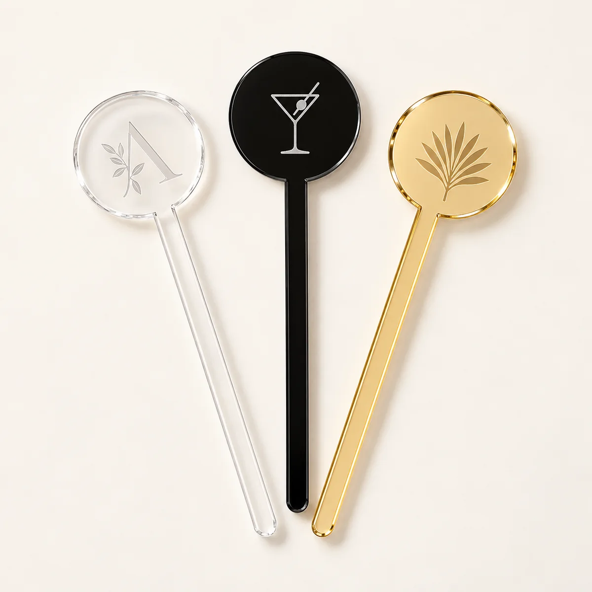 Three custom acrylic drink stirrers in clear, black and gold mirror